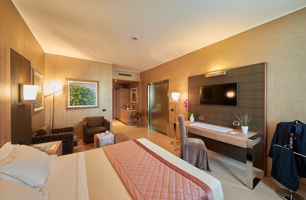 A hotel room with a bed, a desk, a chair, a TV, and a bathroom.