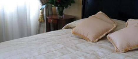 A bed with a quilted cover and two pillows.