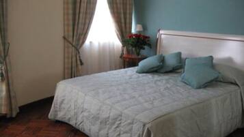 A bedroom with a bed, a nightstand, a lamp, and a window with curtains.