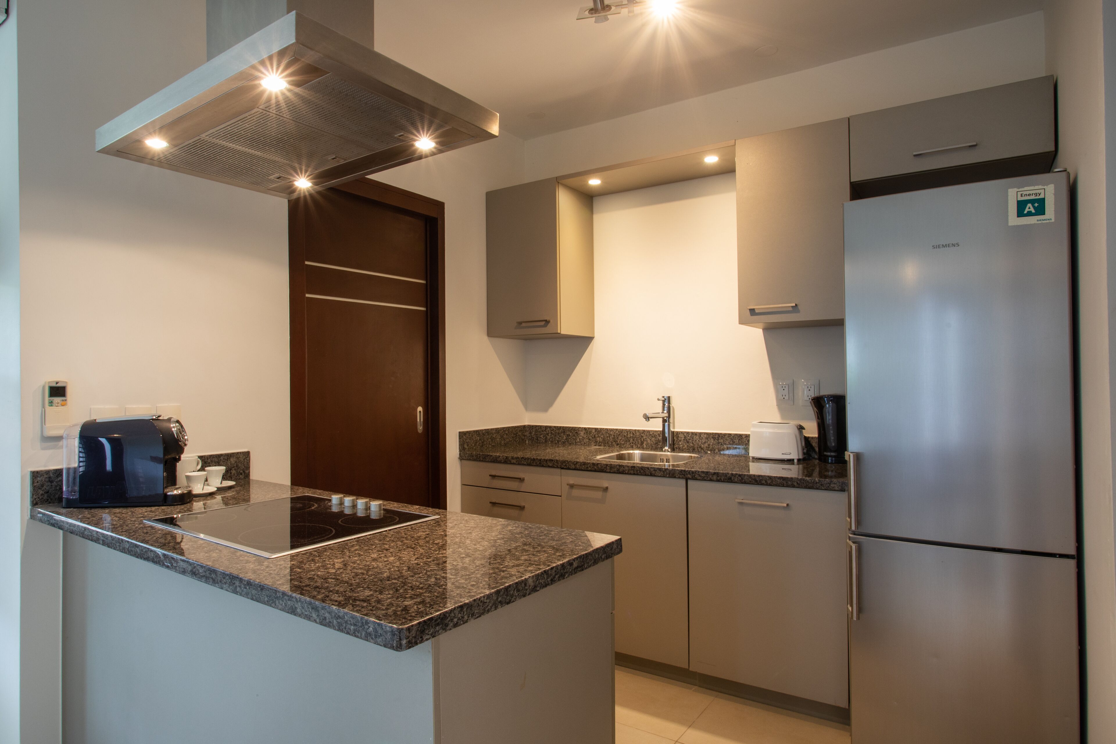 A modern kitchen with a built-in stove, a refrigerator, and a coffee maker.