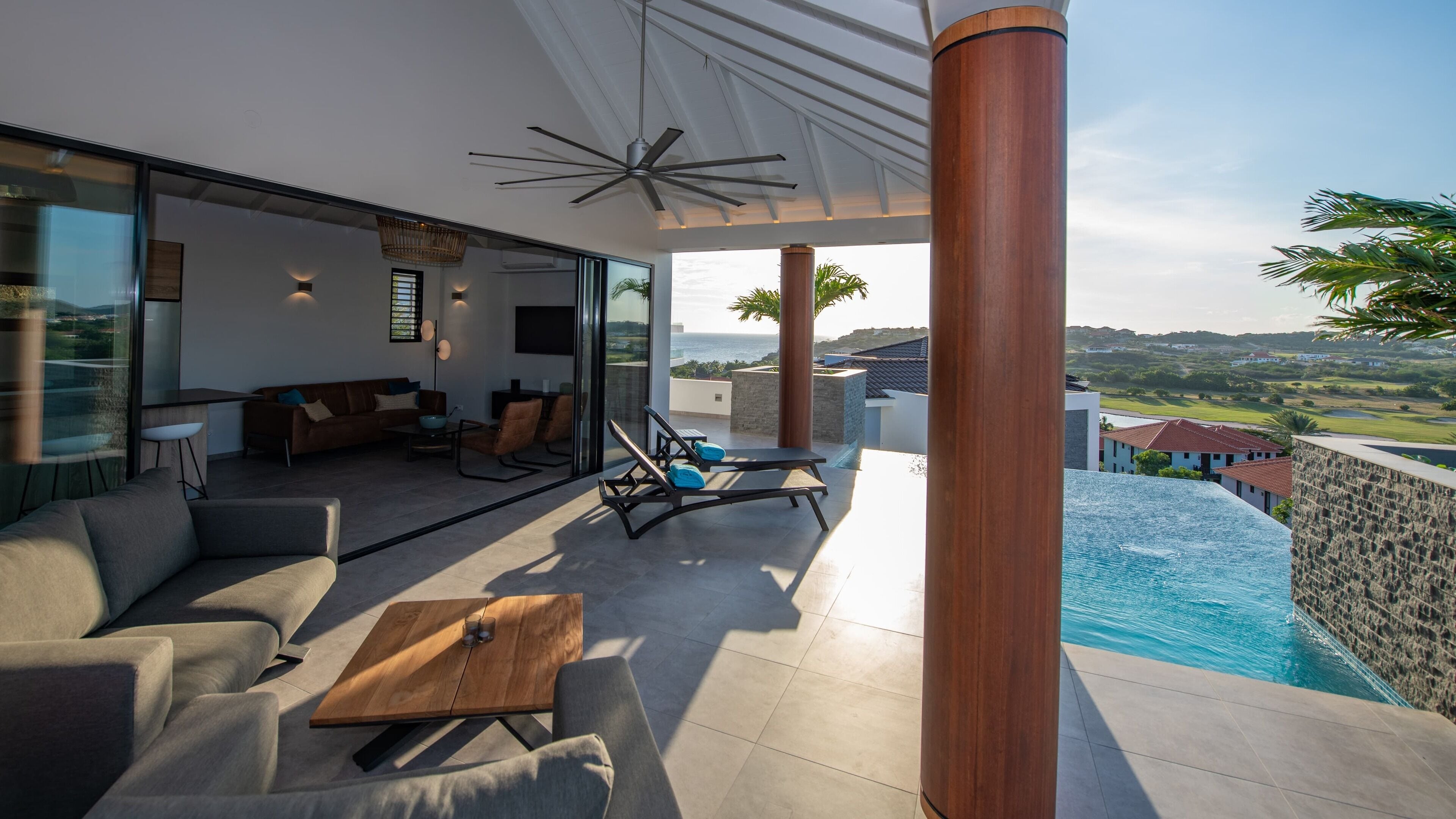 A modern outdoor living area with a pool, seating, and a view of the landscape.