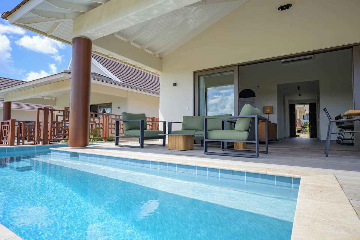 Une piscine avec des chaises longues et un espace patio couvert.