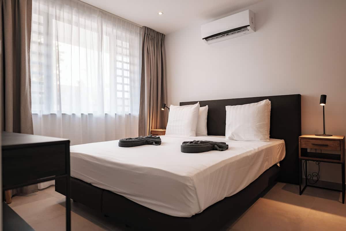 Une chambre d’hôtel avec un grand lit, un bureau, une table de chevet et un appareil de climatisation.