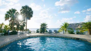 Alberca al aire libre, sombrillas en la alberca y camastros