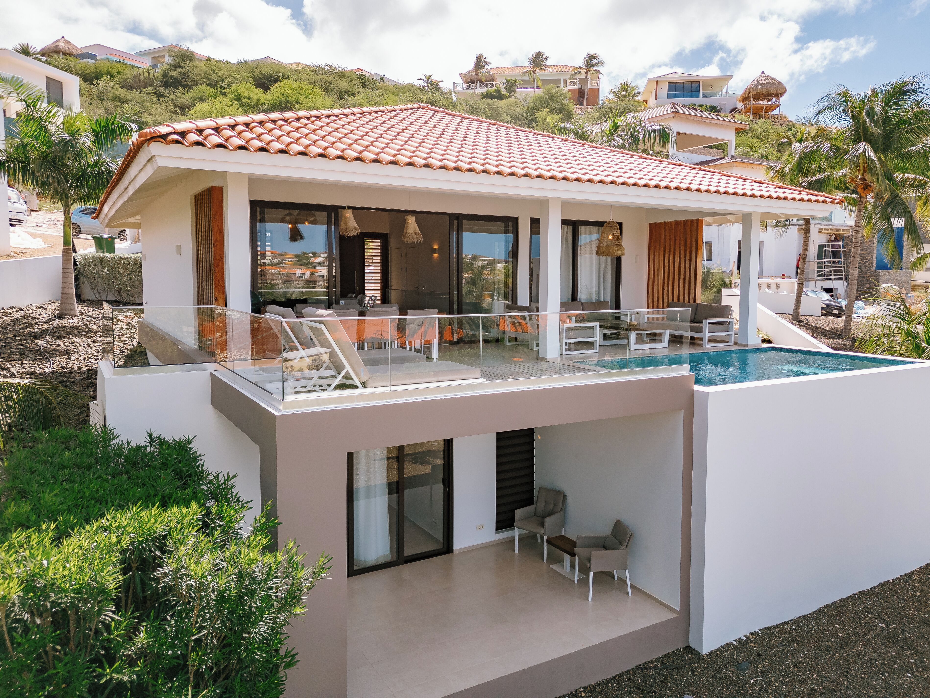 Una casa moderna con piscina, un patio cubierto y vistas del paisaje circundante.