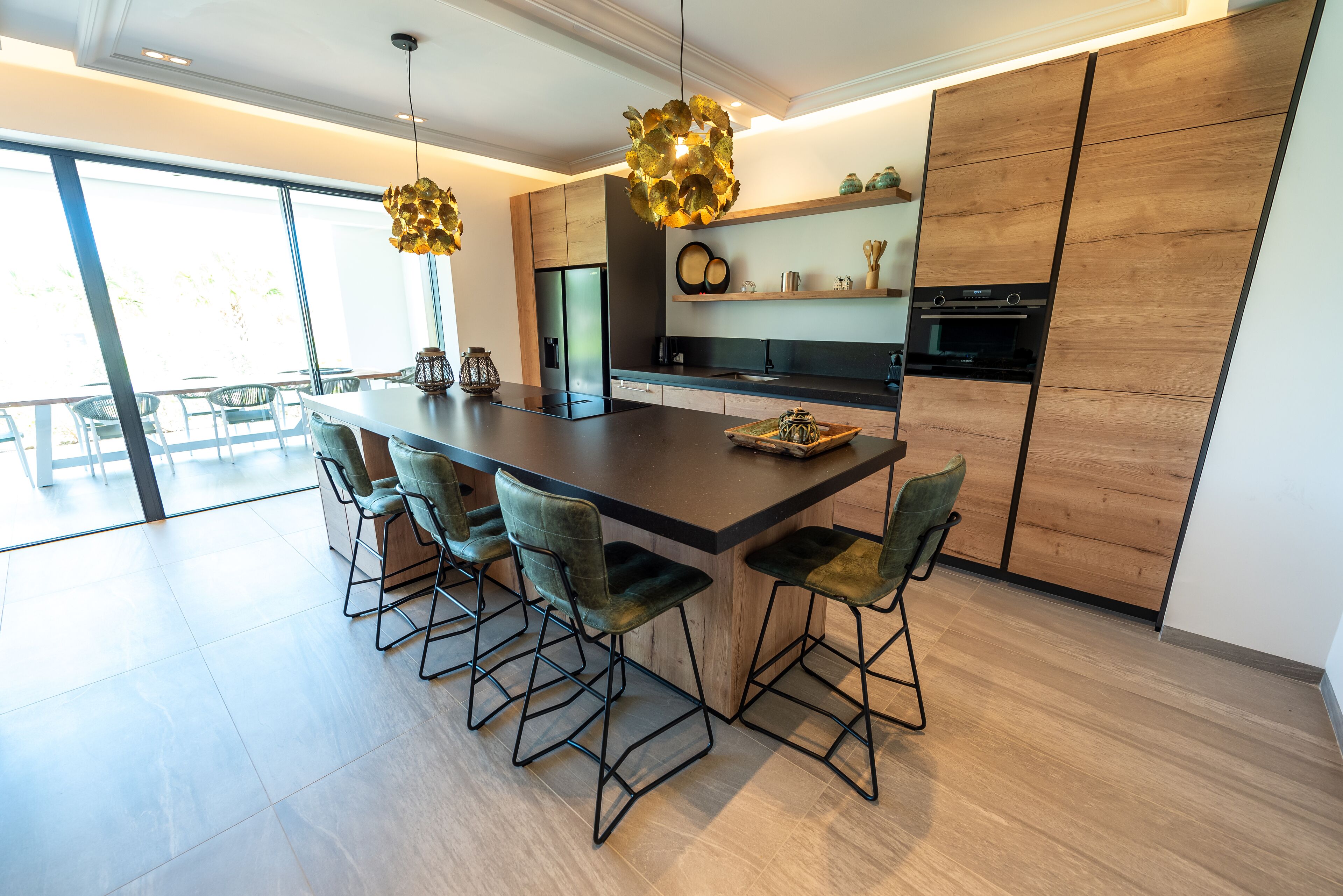 Una cocina moderna con una isla grande, taburetes de bar y lámparas colgantes.