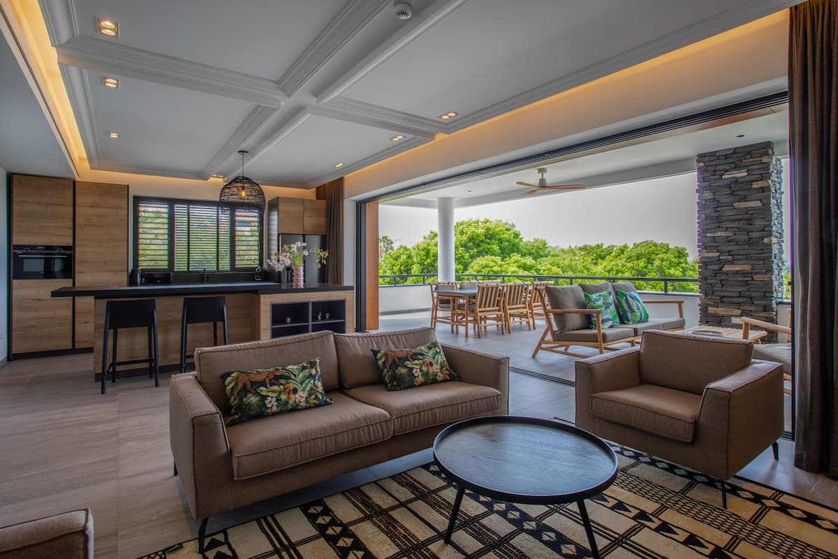Une cuisine moderne avec un coin repas, un canapé et un balcon offrant une vue sur la verdure.