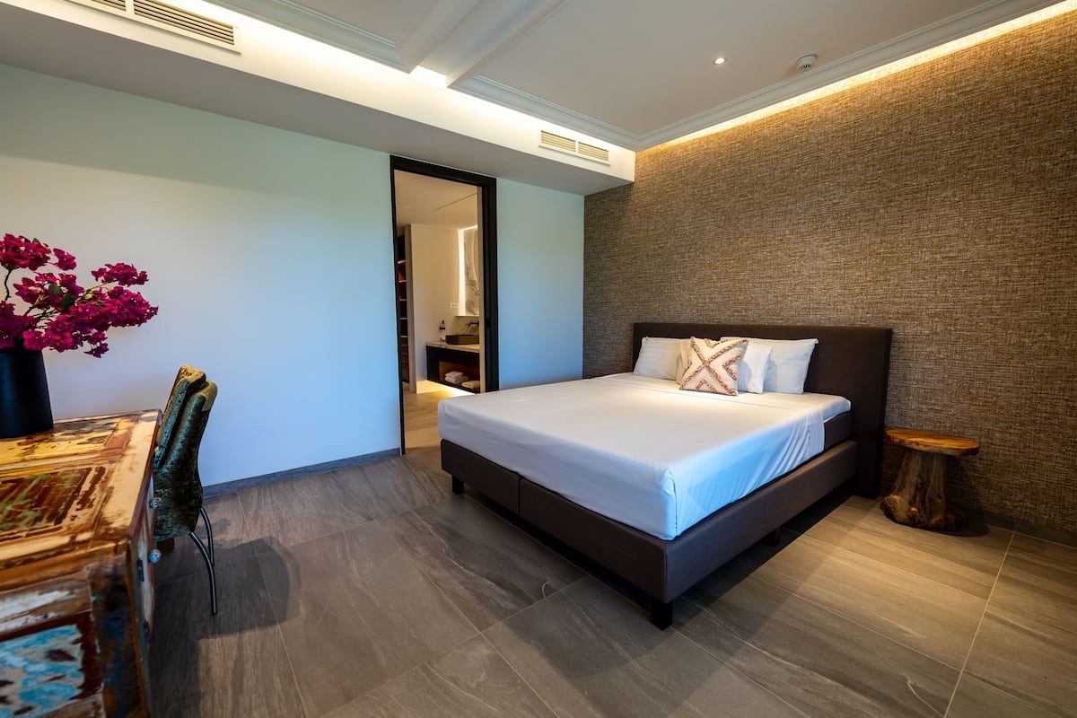 Une chambre moderne avec un grand lit, une table de chevet en bois et une chaise.
