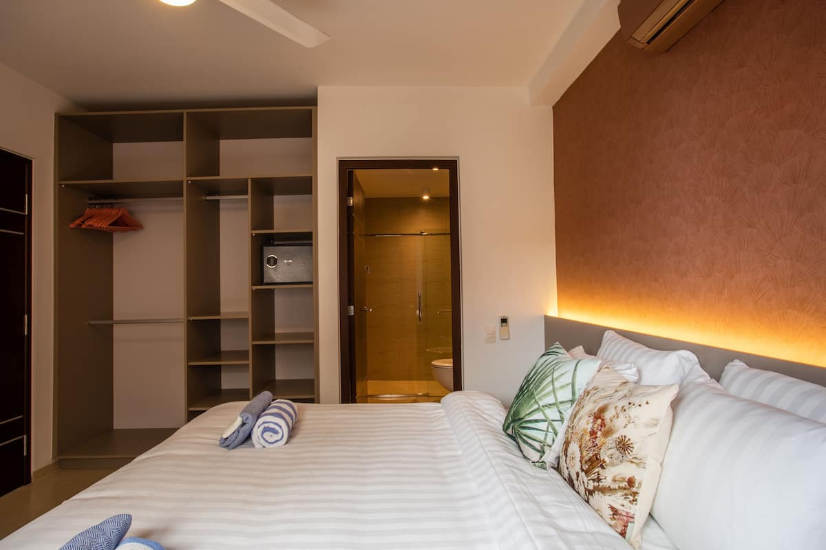 Une chambre d’hôtel avec un grand lit, un dressing et un espace douche.