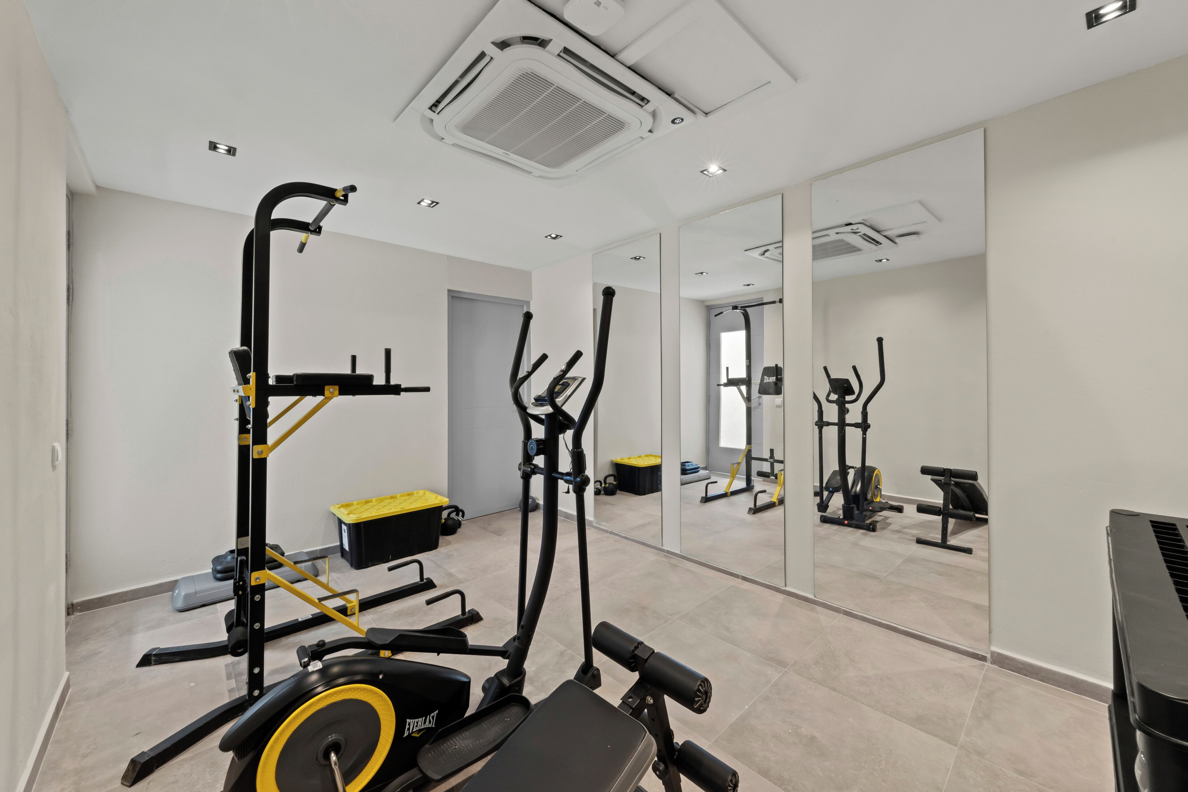 Un gimnasio con equipo de ejercicio, un espejo grande y un piano.