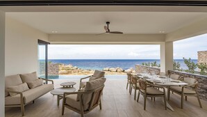 Un vaste espace de vie avec vue sur la mer, un ventilateur de plafond et une table à manger pour quatre personnes.