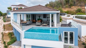 Une maison moderne dotée d’une piscine, de mobilier d’extérieur et offrant une vue sur le paysage environnant.