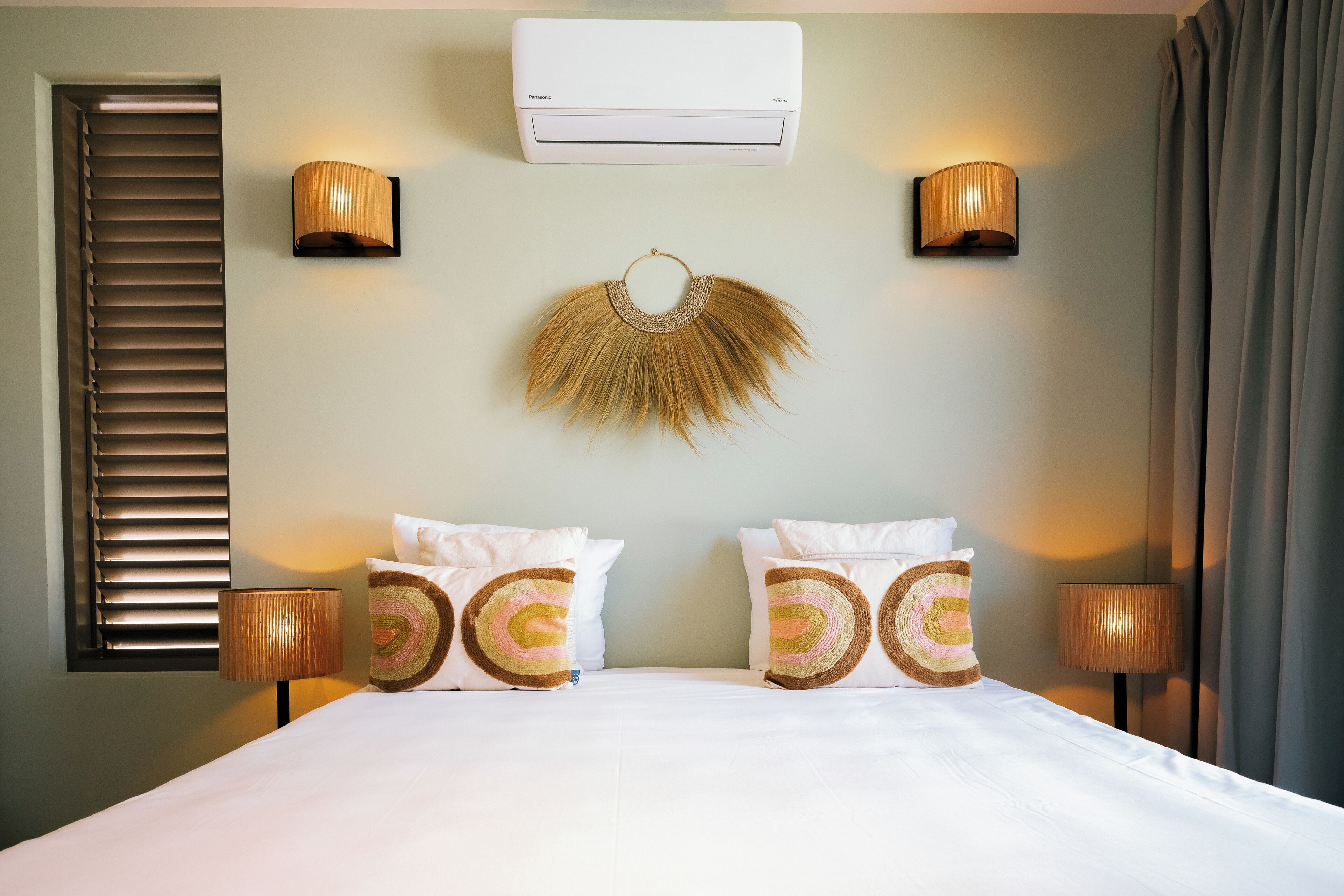 Ein Hotelzimmer mit einem Bett, zwei Wandlampen, einer Klimaanlage und einem Wanddekor.