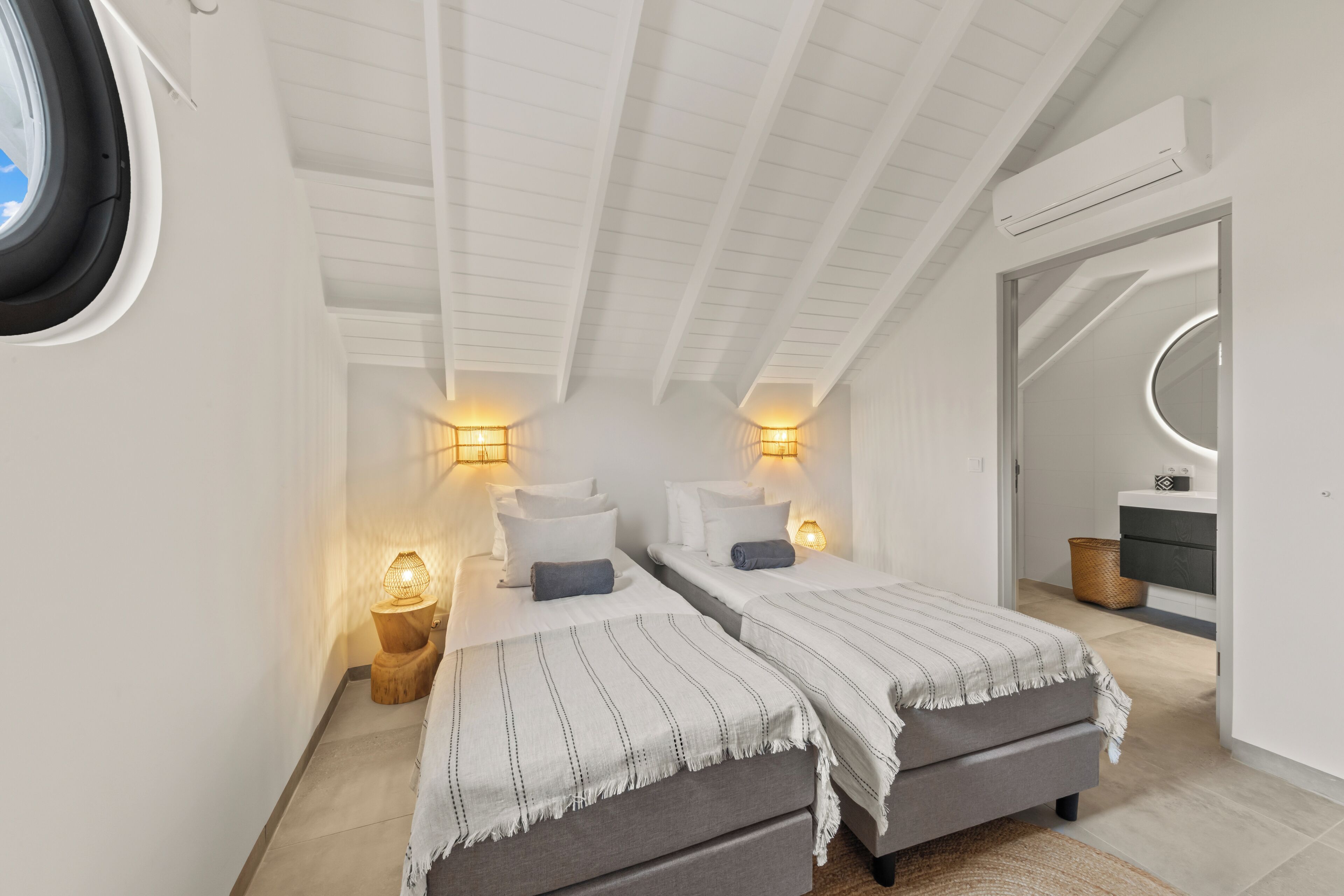 Une chambre avec deux lits, une fenêtre et un ventilateur de plafond.