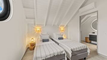Une chambre avec deux lits, une fenêtre et un ventilateur de plafond.