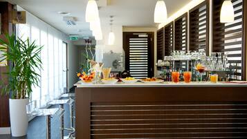 A modern bar area with a long counter, clear glassware, and a variety of beverages.