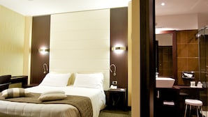 Een moderne hotelkamer met een groot bed, een bureau en een badkamer met een spiegel en wastafel.