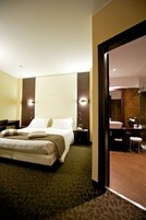 Una camera d'hotel moderna con un letto grande, una scrivania e un bagno con uno specchio e un lavandino.