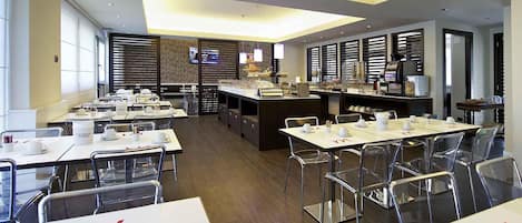 A modern restaurant with multiple tables, chairs, and a central bar area.