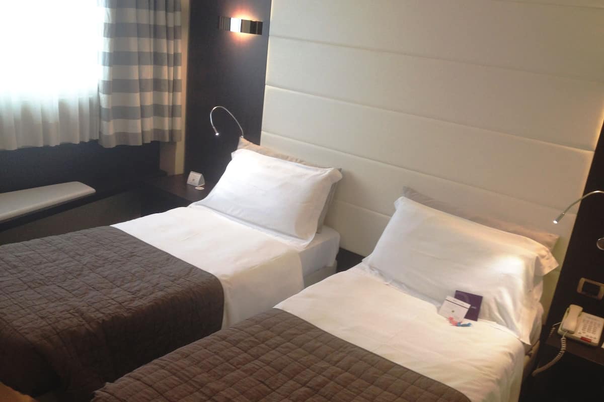 Habitación de hotel con dos camas, una mesita de noche, una lámpara y un teléfono.