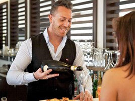 Un cameriere versa una bevanda in un bicchiere al bar.