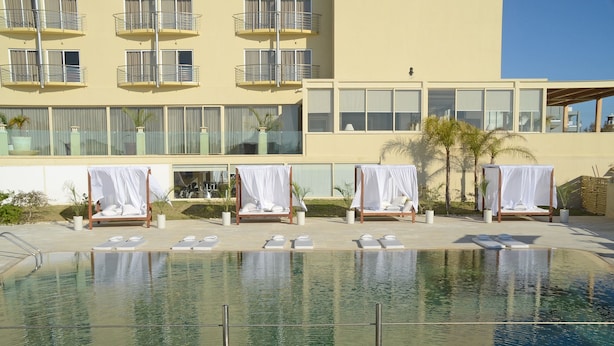 A hotel with a pool area featuring sun loungers and covered beds. - E Hotel Spa & Resort Cyprus (Pervolia)