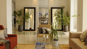 A modern living room with a glass coffee table, red and beige sofas, and large potted plants. - E Hotel Spa & Resort Cyprus (Pervolia)