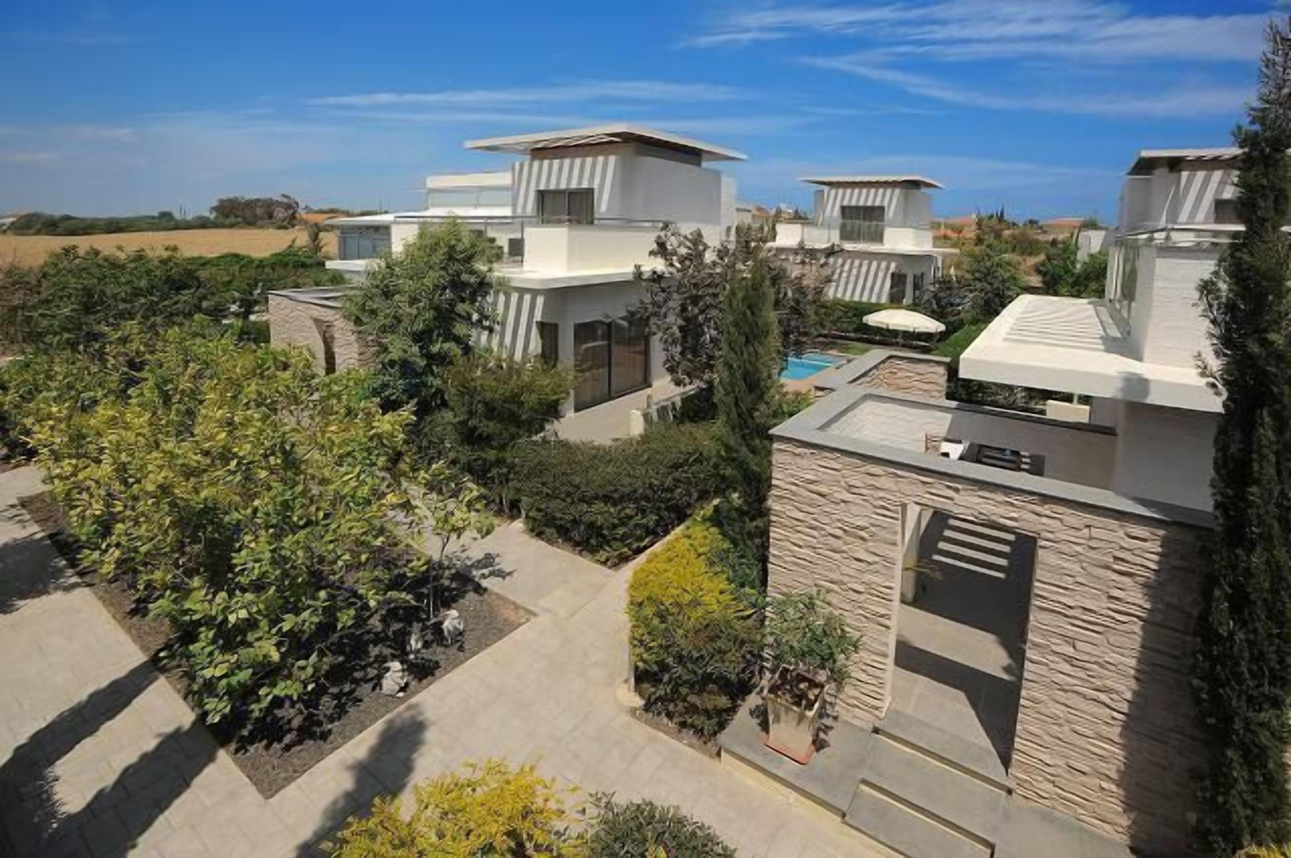 Un complejo residencial moderno con varias casas, piscina y jardines bien cuidados.
