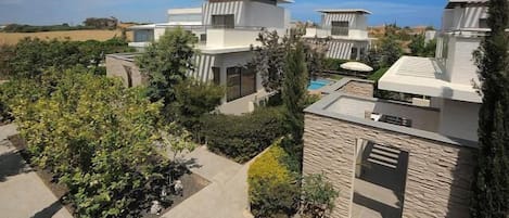 Un complejo residencial moderno con varias casas, piscina y jardines bien cuidados.