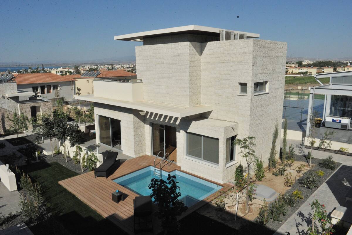 Una casa moderna de dos pisos con piscina, ventanas amplias y vista al mar.