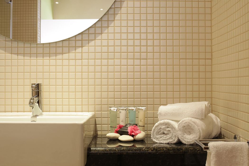 A bathroom with a sink, mirror, toiletries, and towels.