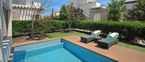 A modern pool area with two lounge chairs and a clear blue pool.