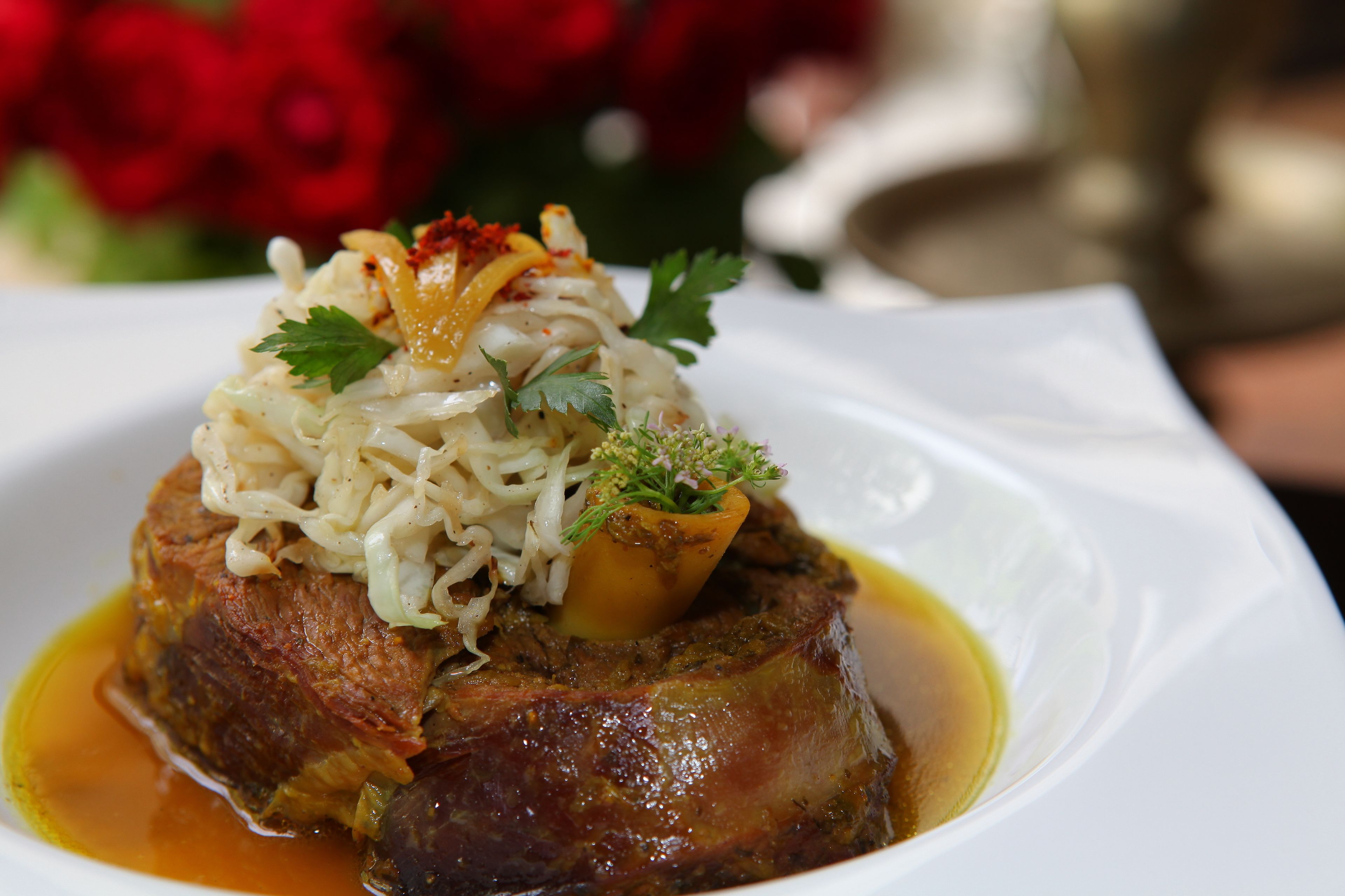 A dish with meat, vegetables, and sauce on a white plate.