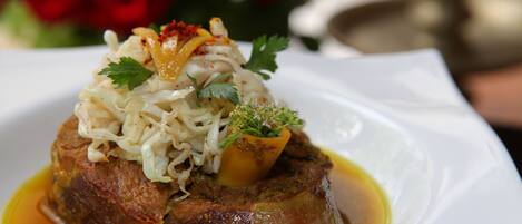 A dish with meat, vegetables, and sauce on a white plate.