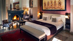 A spacious bedroom with a large bed, a fireplace, a painting, and a red carpet. - Le Riad Monceau (Marrakech)