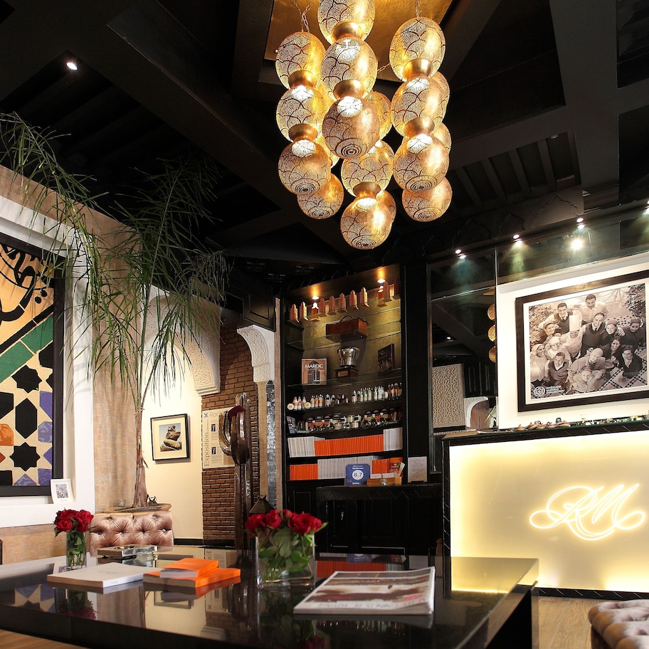 A reception area with a modern chandelier, a large decorative wall, and a neon sign.