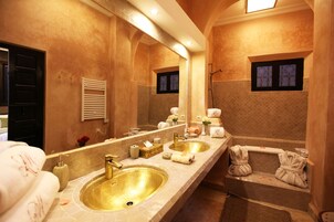 Un baño lujoso con un espejo grande, dos lavamanos, una bañera y una ducha.