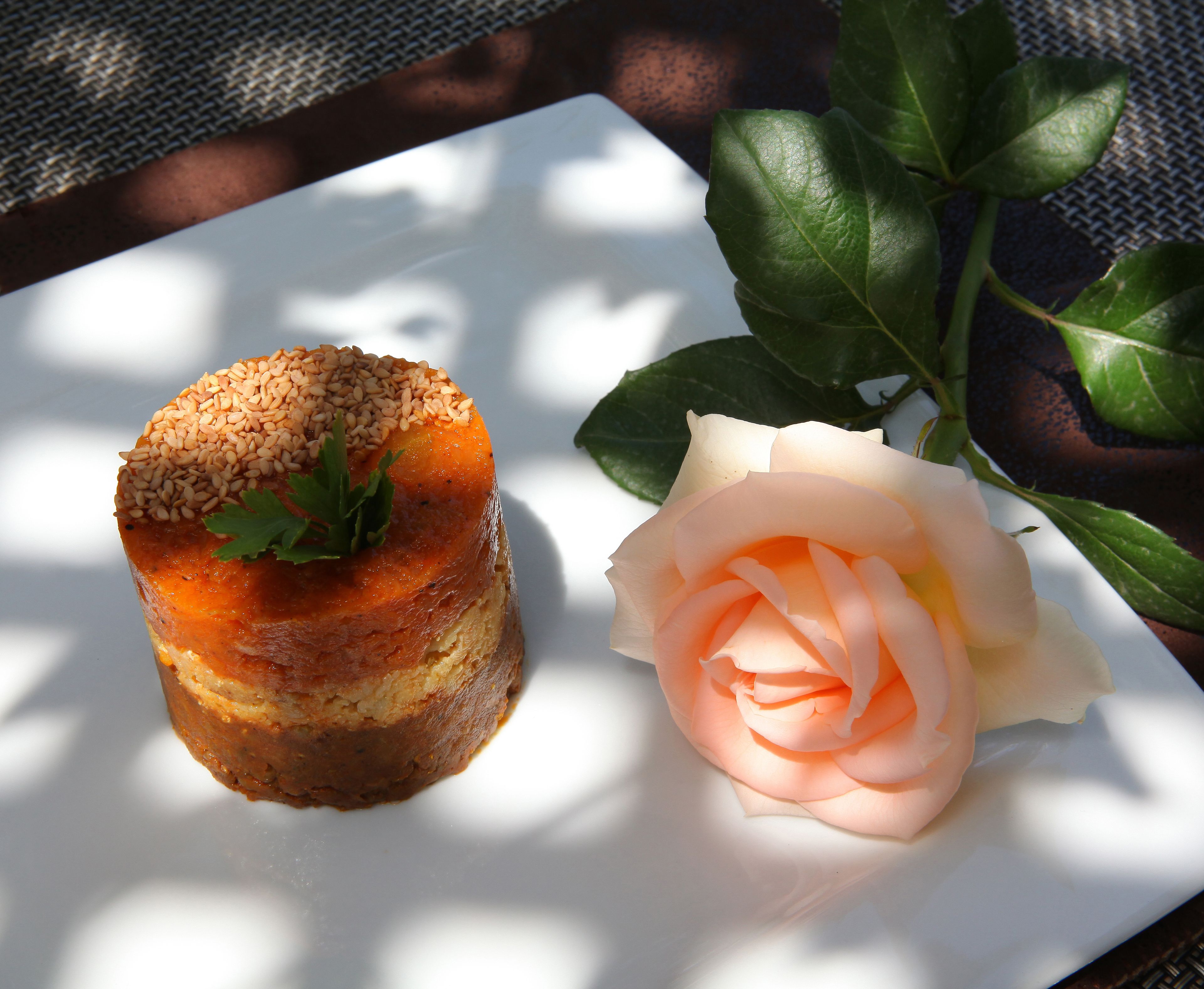A plate with a food item topped with sesame seeds and a rose.