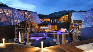 A modern building with a glass facade, outdoor seating area, and a pool. - Wellness Hotel Sotelia (Podcetrtek)
