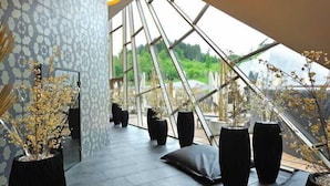 Un interior moderno con techo de cristal geométrico, plantas en macetas y pared con diseño.