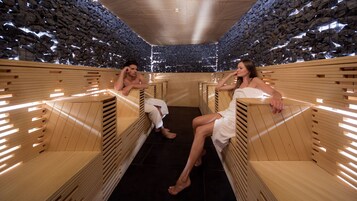 Una sauna con bancos de madera y un fondo de pared de piedra.
