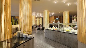 A modern hotel lobby with a central reception desk, high ceilings with recessed lighting, and a buffet area with various food items. - Wellness Hotel Sotelia (Podcetrtek)