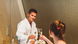A man in a white robe sitting at a table with a woman, both holding wine glasses. - Wellness Hotel Sotelia (Podcetrtek)