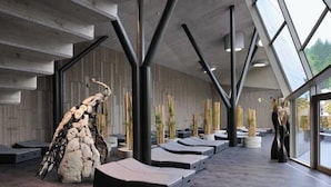 Un interior moderno con un diseño arquitectónico único, que presenta una gran escultura de roca, zonas de descanso y vistas a través de amplios ventanales.