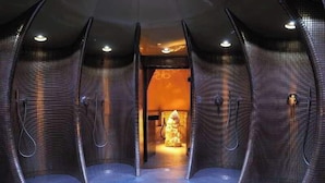 Un cuarto de spa con paredes curvas, una fuente de luz central y una zona de estar.