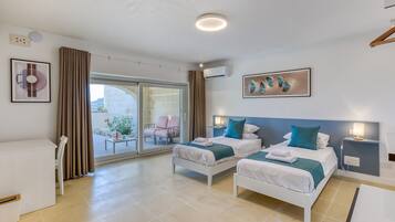 Una camera d'albergo con due letti, un balcone e vista sull'esterno.
