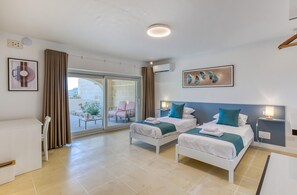 A hotel room with two beds, a balcony, and a view of the outdoors. - Villagg Tal Fanal (Ghasri)