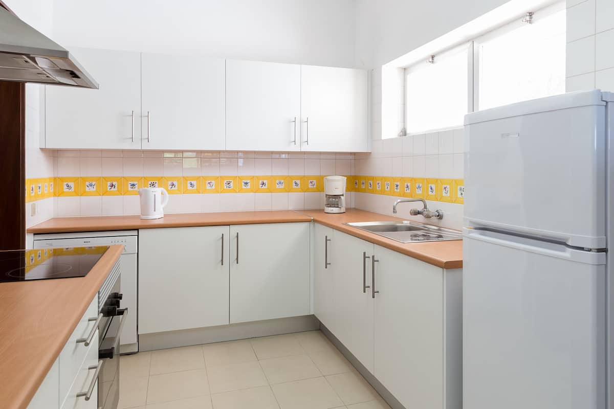 A modern kitchen with white cabinets, a stainless steel sink, and a built-in oven.