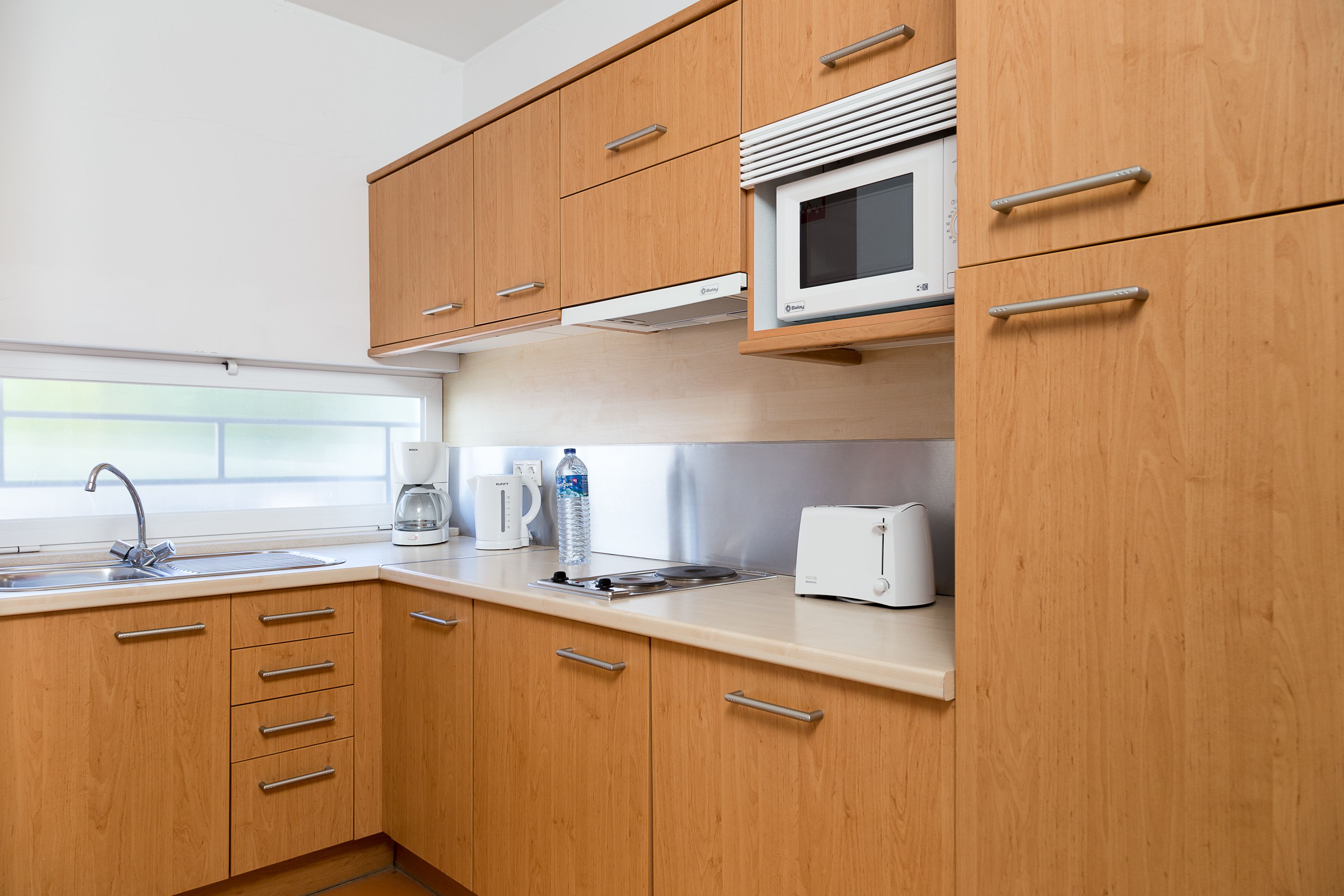 A modern kitchen with wooden cabinets, a microwave, a toaster, and a coffee maker.