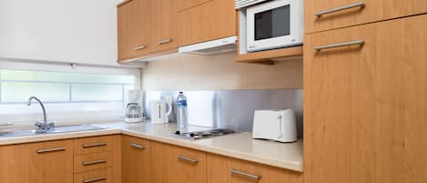 A modern kitchen with wooden cabinets, a microwave, a toaster, and a coffee maker.
